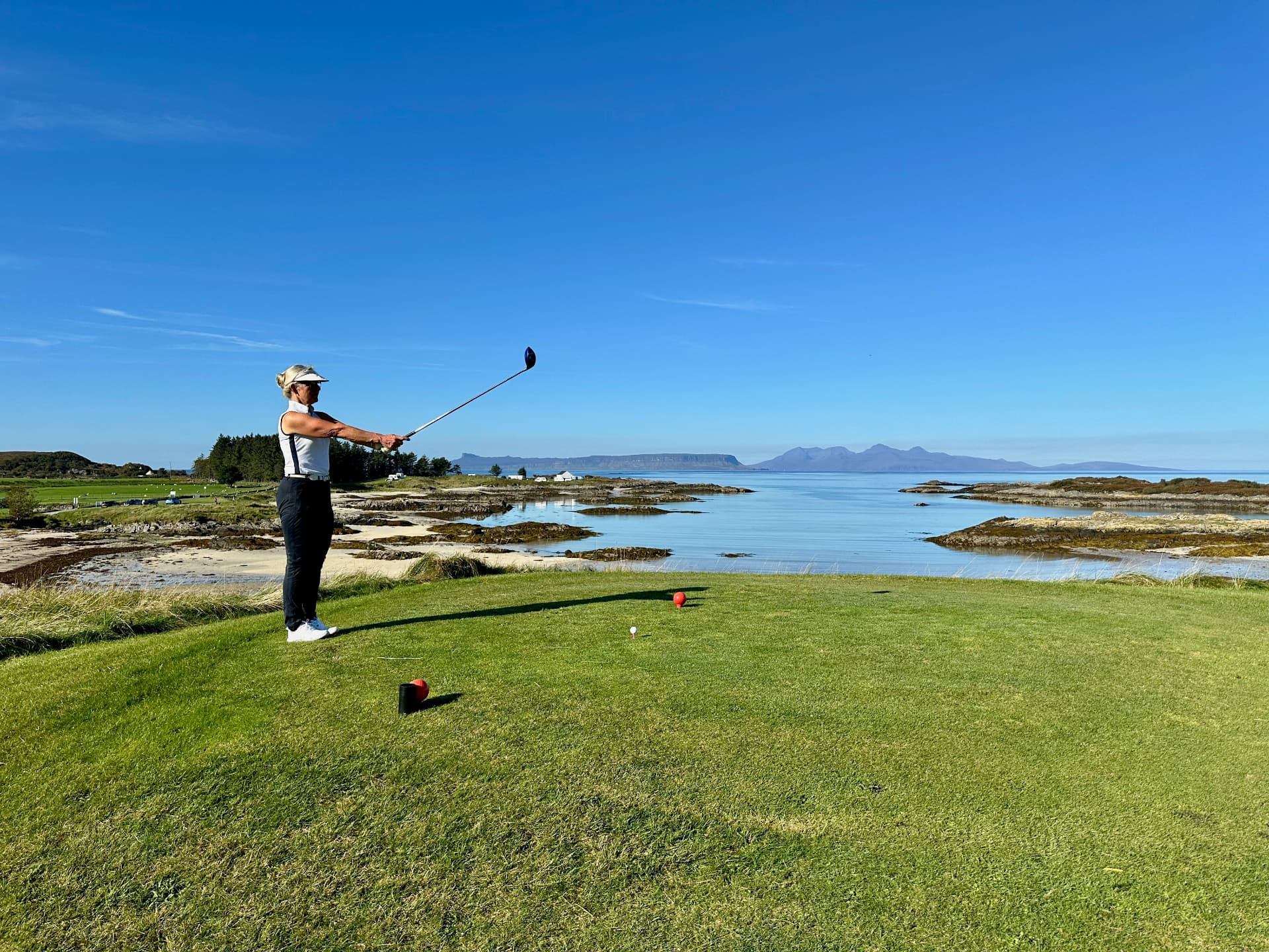 Golfer teeing off beside the sea in Scotland